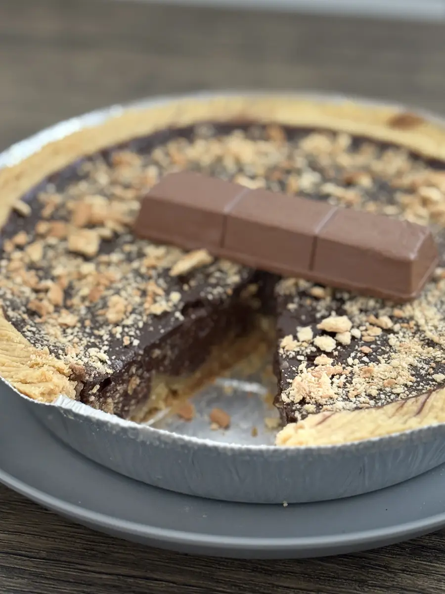 Loyang Kue Lontar cokelat lumer yang sudah dipotong, bertabur remahan Regal dengan batang cokelat di atasnya