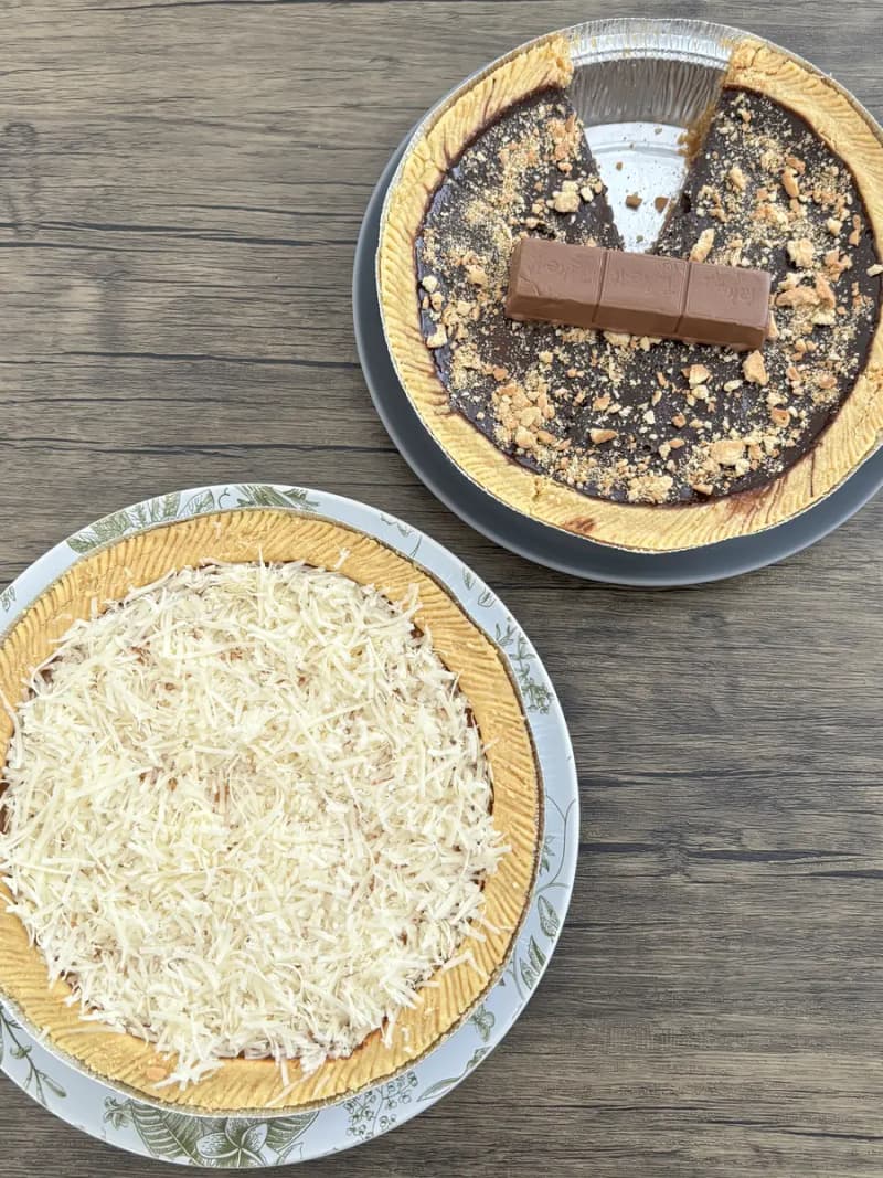 Loyang Kue Lontar keju dan cokelat lumer berdampingan di atas meja kayu, dilihat dari atas
