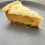 Lontar Slice keju: satu potong Kue Lontar Papua dari samping, lapisan custard tebal di bawah parutan keju cheddar